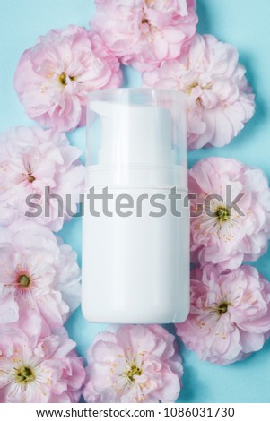 bottle of rose essential oil with rose flowers on a blue background