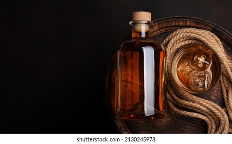 Bottle with rum, cognac or whiskey. Over old wooden barrel. Top view flat lay with copy space - Shutterstock ID 2130245978