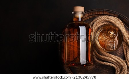 Bottle with rum, cognac or whiskey. Over old wooden barrel. Top view flat lay with copy space