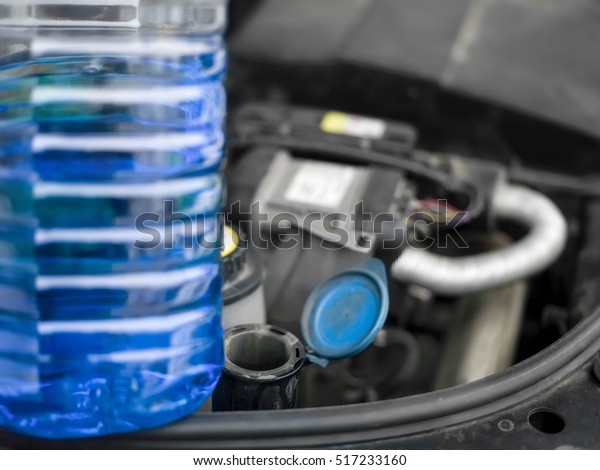 A bottle of a screen washer fluid and a car\
boot open, shallow depth of field\
shot