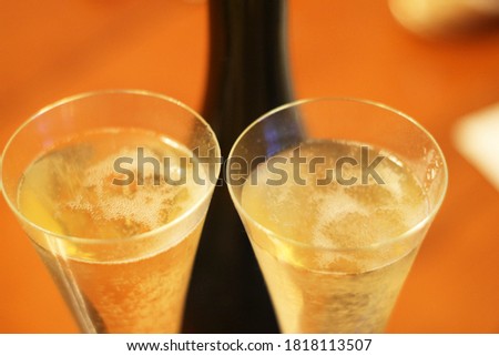 Bottle of shampagne and a two full glasses of cold shampagne before drinking on the wooden background
