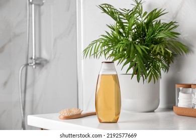 Bottle of shampoo and hairbrush on white table near shower stall in bathroom, space for text