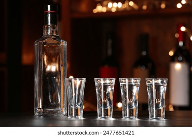 Bottle and shots of cold vodka on table in bar