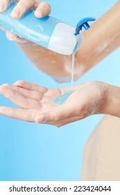 Bottle of shower gel in woman's hands on blue background