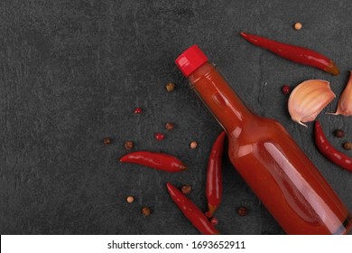 Flasche mit scharf roter Sauce auf schwarzem Hintergrund