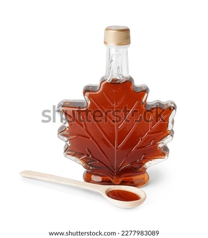 Bottle and spoon of tasty maple syrup on white background