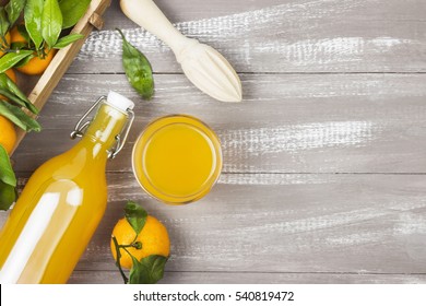 Bottle of tangerine juice and fresh fruit on a wooden background. Top view, copy space. Food background.