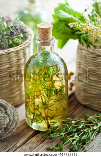 Bottle of thyme essential oil or infusion and\
basket with healing\
herbs.