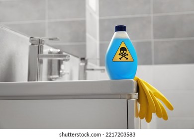 Botella de sustancia química doméstica tóxica con señales de advertencia y guantes en el baño, espacio para texto