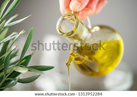 Bottle of virgin olive oil pouring close up