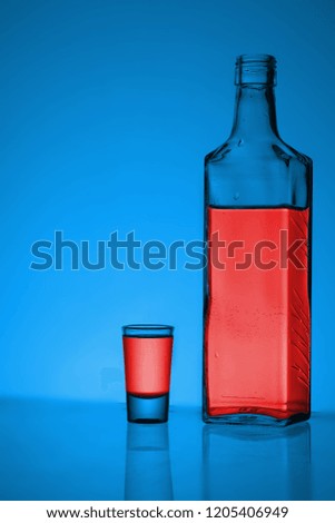 
bottle of vodka with a glass on a colored background