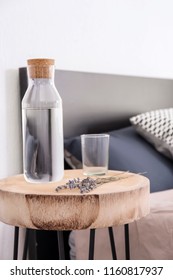 Bottle Of Water And Beautiful Lavender Flowers On Table In Bedroom