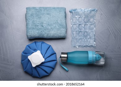 Bottle Of Water, Cold Compress, Ice Pack And Towel On Grey Background, Flat Lay. Heat Stroke Treatment