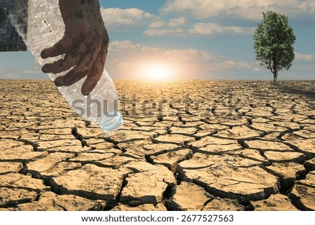 Bottle of water in an empty hand, devoid of water in a hot, dry climate.