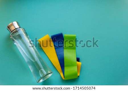bottle of water and fitness elastic band on blue background.Sport trend. Fitness concept
