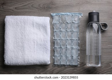 Bottle Of Water, Ice Pack And Towel On Wooden Background, Flat Lay. Heat Stroke Treatment