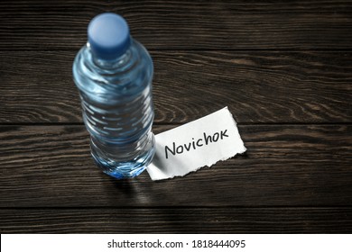 Bottle of water and note Novichok on wooden table. Novichok is agent poison, deadly nerve venom. Concept of Navalny incident, intelligence service, secret attack, hidden threat and poisoning.