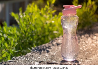 A Bottle Of Water. Reusable Plastic Water Bottle On The Background Of Green Grass. Watered From Above By Raindrops On A Hot Summer Day.