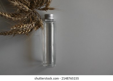 Bottle of wheat juice with dry wheat ears on white table. bottle of wheat water with wheat ears on a white background