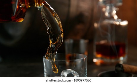 Bottle Of Whisky With Splashing Liquid, Detail Of Pouring. Still Life With Wooden Barell On Background