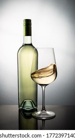 Bottle Of White Wine And A Glass With Swirled Wine