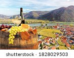 Bottle of white wine with glasses against Weissenkirchen village with autumn vineyards in Wachau valley, Austria