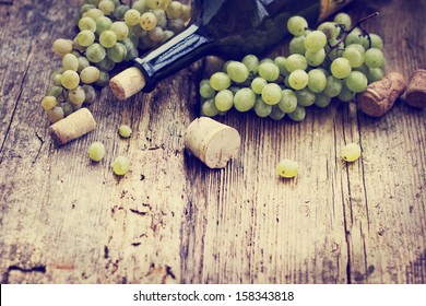 Bottle Of White Wine, Grape And Corks On Wooden Table