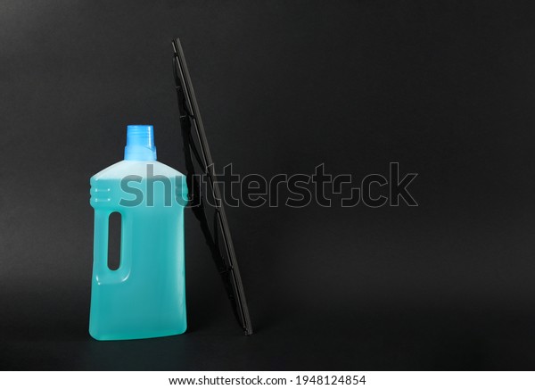 Bottle of windshield washer fluid and wiper on black\
background. Space for\
text