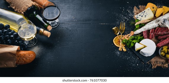 A bottle of wine, cheeses and traditional sausages on a wooden background. Brie cheese, blue cheese, gorgonzola, fuete, salami. Free space for text. Top view. - Powered by Shutterstock