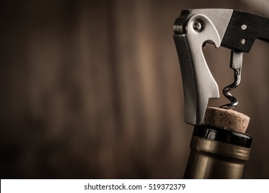 Bottle of wine and corkscrew over wooden background