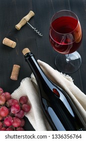 Bottle Of Wine,  Glass Of Wine And  Bunch Of Pink Grapes On Dark Wooden Table. Top View.