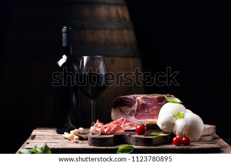 Bottle of wine with a glass on a table with rustic traditional italian food.Fresh tipical italian lifestyle