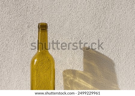 A bottle of wine in sunlight and its colored shadow. long shadow and refraction patterns. White background. Caustic