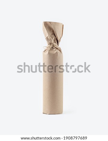 A bottle of wine wrapped in kraft paper. Packed bottle on a light background. Mockup. Side view.