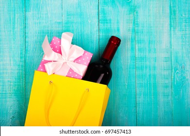 A Bottle Of Wine In A Yellow Package As A Gift, Next Flowers, Gifts, Copy Space, On Blue Wooden Background, To Give Girls A Set Of Gentlemen For Dating