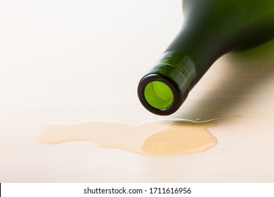 Bottleneck Of Cognac Bottle Over Spilled Liquid On Wooden Board Close Up