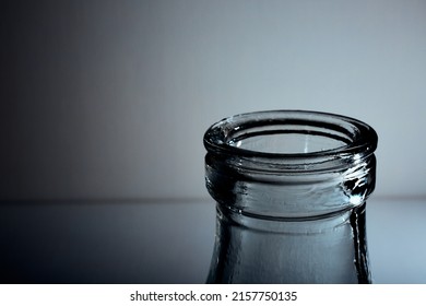 The Bottleneck Of Glass Bottle. Close-up. Copy Space. Graphic Still Life With Light And Shadow In Black And White Colors. Art. Recyclable Materials. Concept Of Alcohol Problems. Depressive Condition.