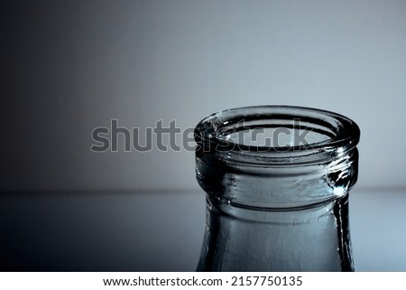 The bottleneck of glass bottle. Close-up. Copy space. Graphic still life with light and shadow in black and white colors. Art. Recyclable materials. Concept of alcohol problems. Depressive condition.