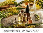 Bottles of aromatherapy essential oil with fresh blooming agrimony or sticklewort plant