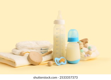 Bottles with baby milk formula, toys, diapers and pacifier on color background