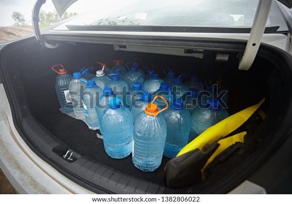 Bottles of blue\
water in the trunk of a white\
car