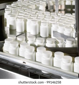 Bottles coming out of the pill counter in a pharmaceutical processing facility.