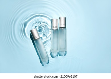 Bottles of cosmetic products in water on blue background - Shutterstock ID 2100968107