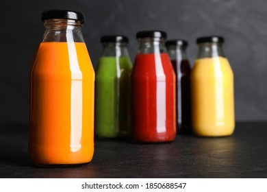 Bottles with delicious colorful juices on black table