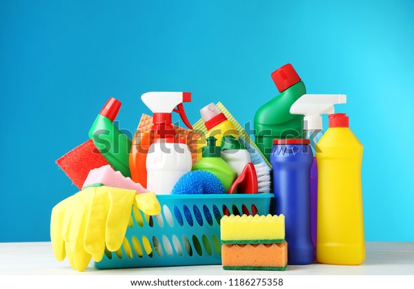 Bottles with detergent and cleaning tools on\
blue background