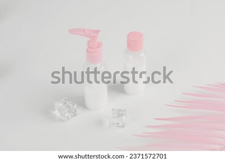 bottles with a dispenser for shampoo, soap. Set of two pink jars for use on a travel on soft white background. Beauty cosmetics glassbottle, branding mock up. Toiletries, shampoo, lotion, shower gel