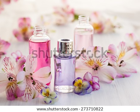 Bottles of essential aromatic oils surrounded by fresh flower