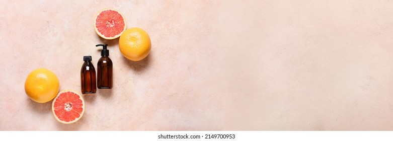 Bottles Of Essential Oil And Grapefruits On Color Background With Space For Text