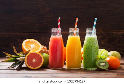 Bottles Of Fruit Juice And Smoothie With Fresh Fruits On Wooden Table