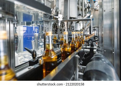 Bottles of golden alcohol with caps transported by conveyor